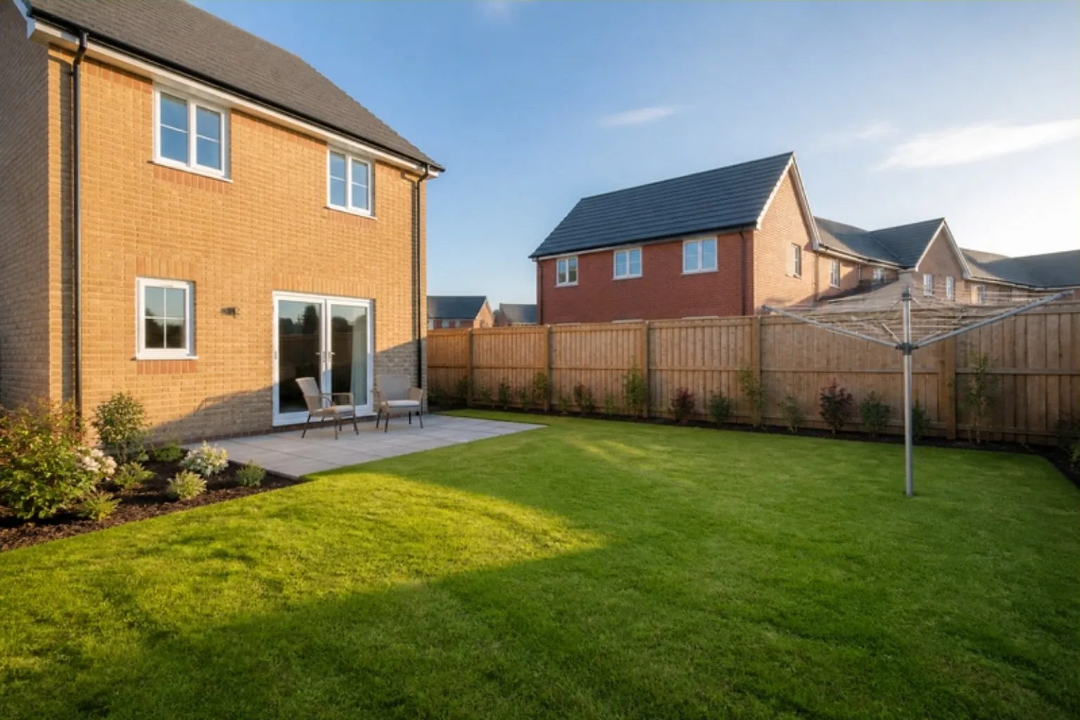 New-build back garden with a fresh square lawn, grey slab patio, timber fence and rotary washing line